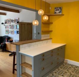 A series of 3 and 4 drawer units with a custom made angled unit on the far end painted in silver grey with a custom made open storage shelving unit with solid oak shelves.  Solid granite worktop and solid oak breakfast bar: Click Here To View Larger Image